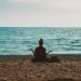 person doing yoga on seashore during daytime